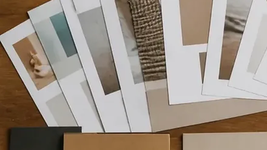 Printed pages and paper samples fanned out on a pale table